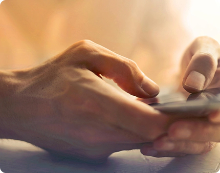 A person is using their cell phone on the table.