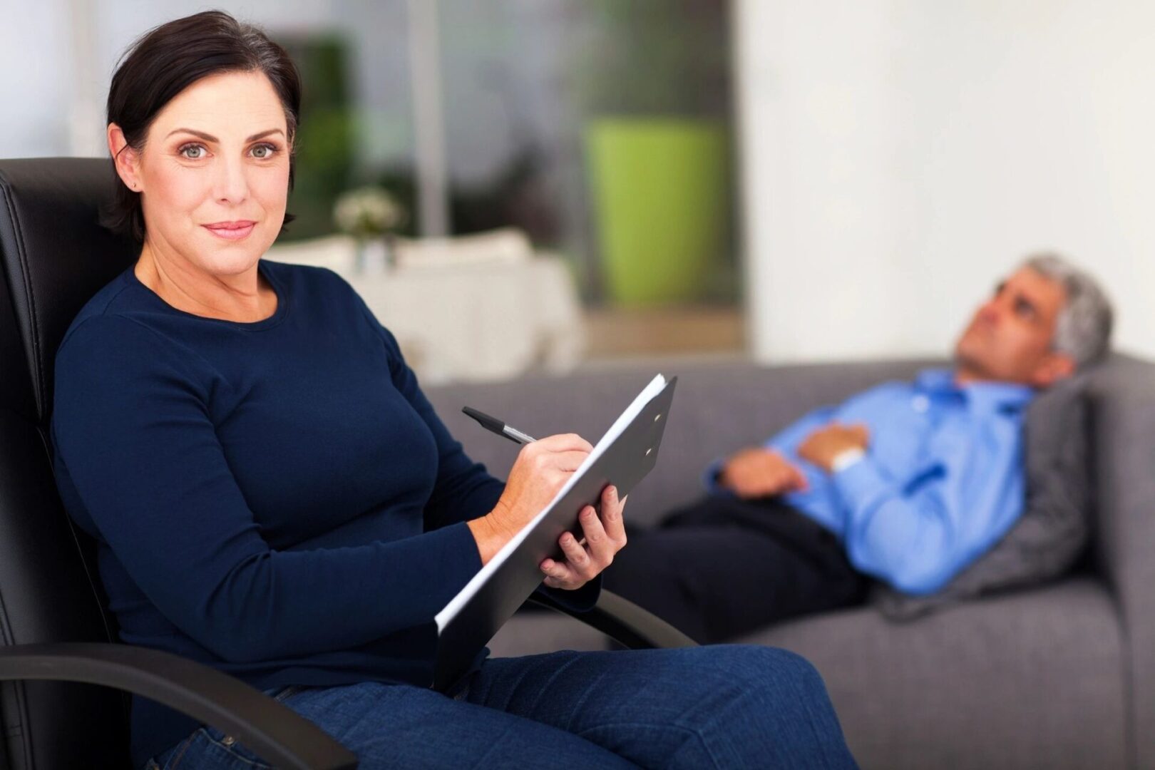 A woman sitting on the couch writing in her notebook